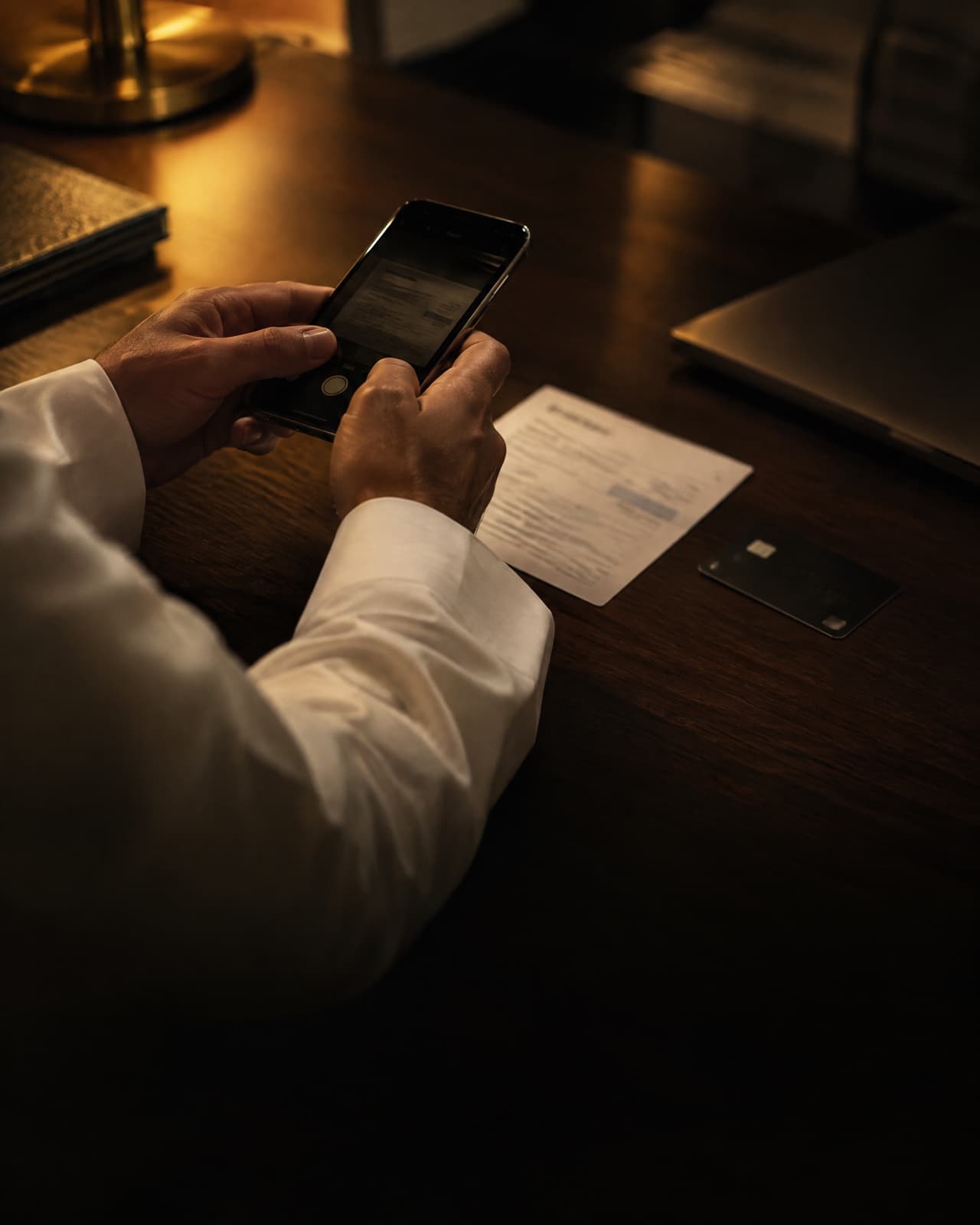 A hand taking a photo of a bank transfer receipt with a phone.